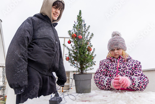 Family decorates a Christmas tree outdoors in winter