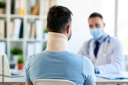 Person in Neck Brace Discussing Health Concerns with Doctor in Medical Office Setting