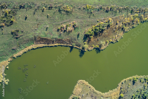 Green river curve and autumn meadow textures with vibrant natural patterns in a drone shot
