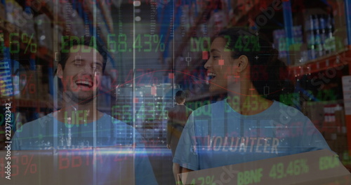 In warehouse, volunteers focusing on teamwork with stock market data overlay