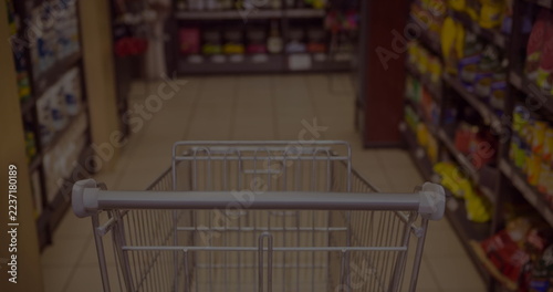 Shopping cart moving through grocery store aisle filled with colorful products