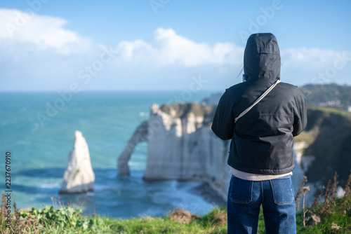 Touriste contemplant les falaises et l’arche naturelle d’Étretat en Normandie