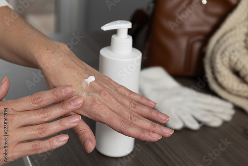 Closeup of a woman applying moisturizer to her hands at a home bathroom vanity